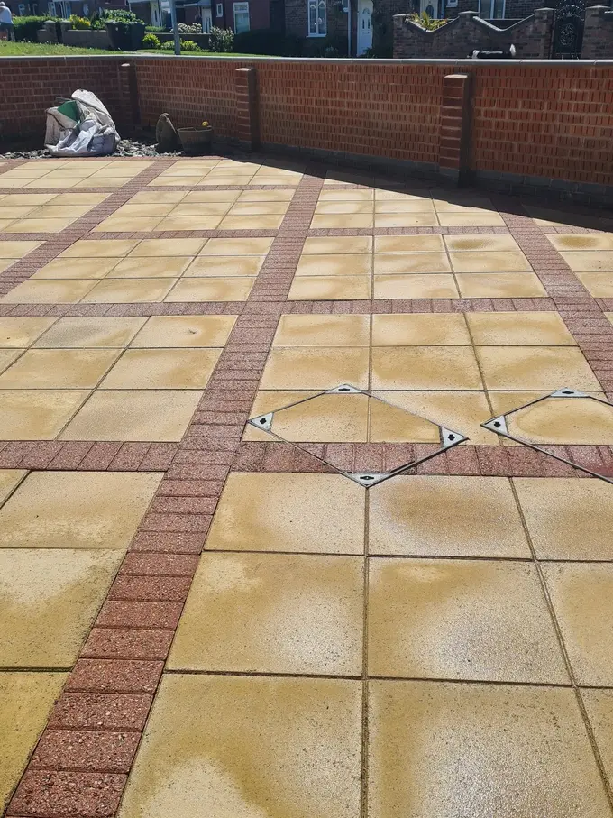 Buff sandstone patio with a brick border washed back to its natural colour