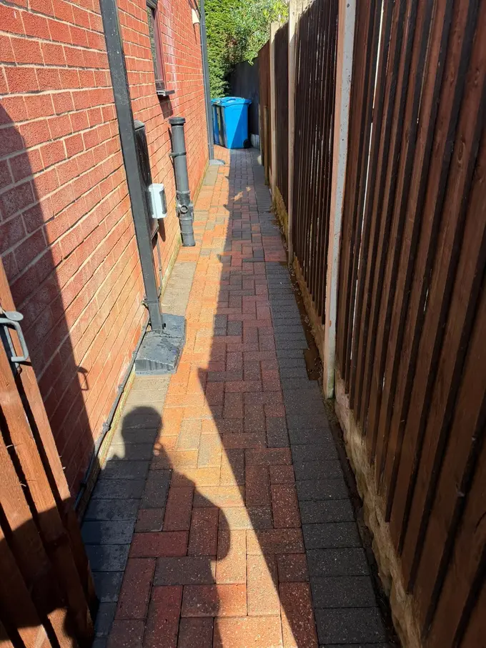 Red block paving path cleaned between the house and fence