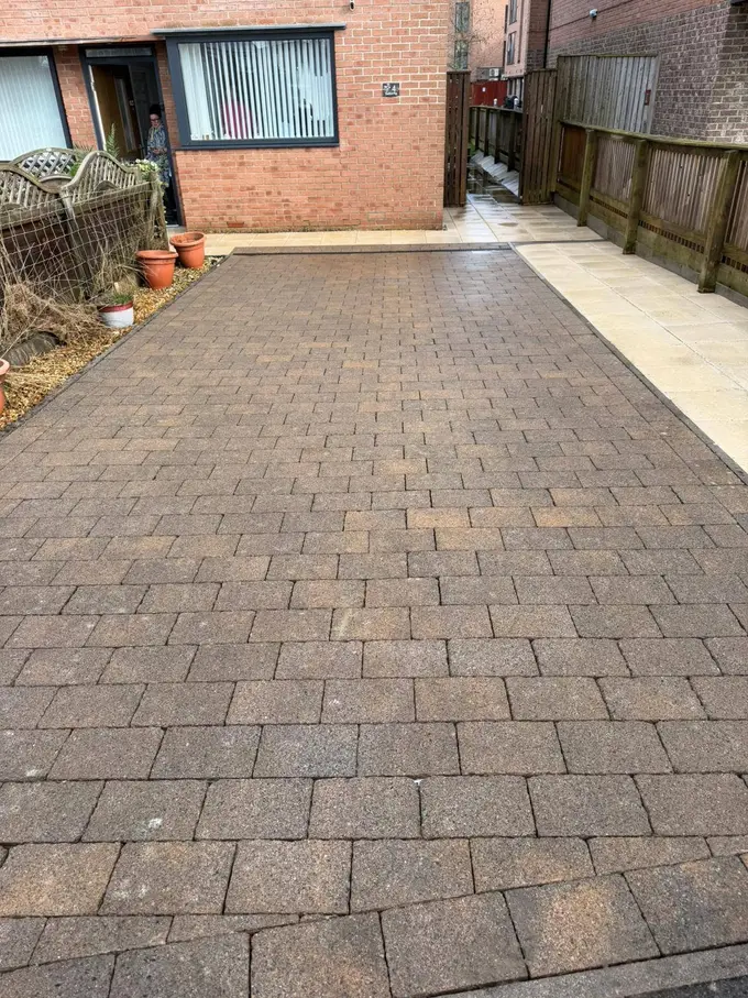 Block paving driveway with a flag border cleaned back to colour