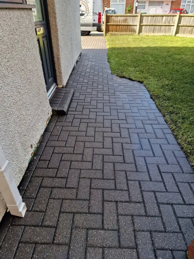 Charcoal block paving path cleaned alongside the lawn