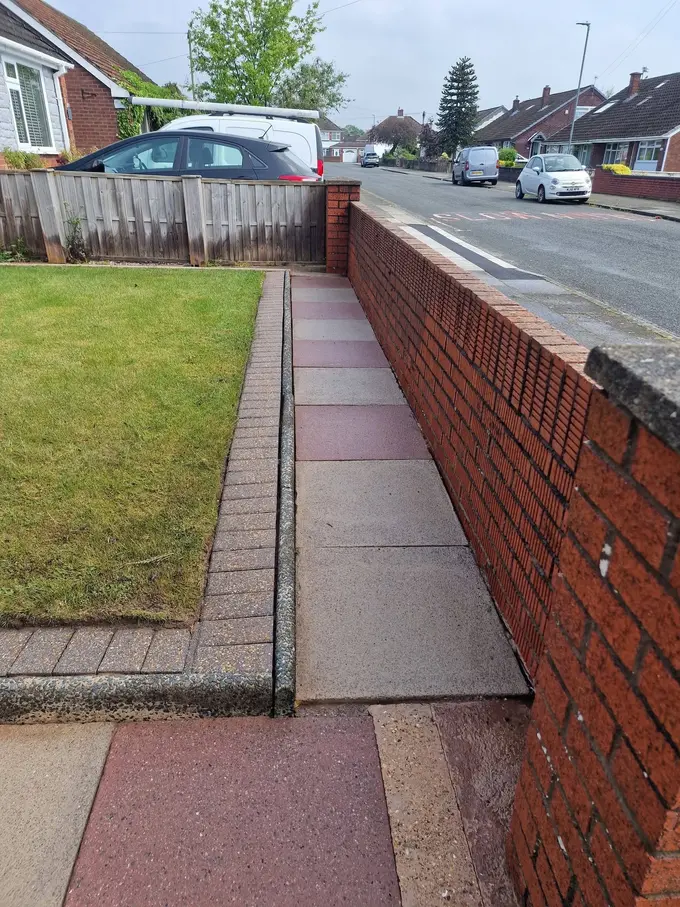 Block paving path cleaned alongside a brick wall