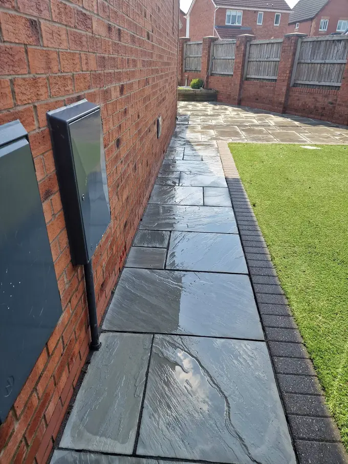 Riven grey patio flags cleaned alongside the lawn